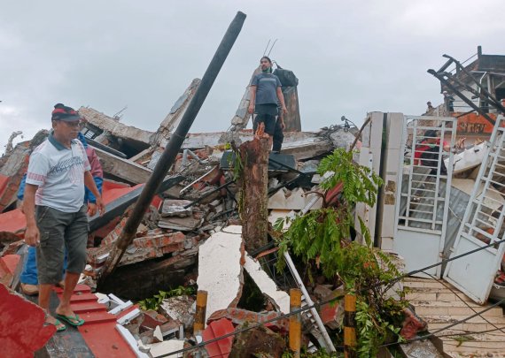 15일 인도네시아 서부 술라웨시 마무주 주민들이 이날 발생한 규모 6.2 지진으로 피해를 입은 건물들을 살펴보고 있.AP뉴시스