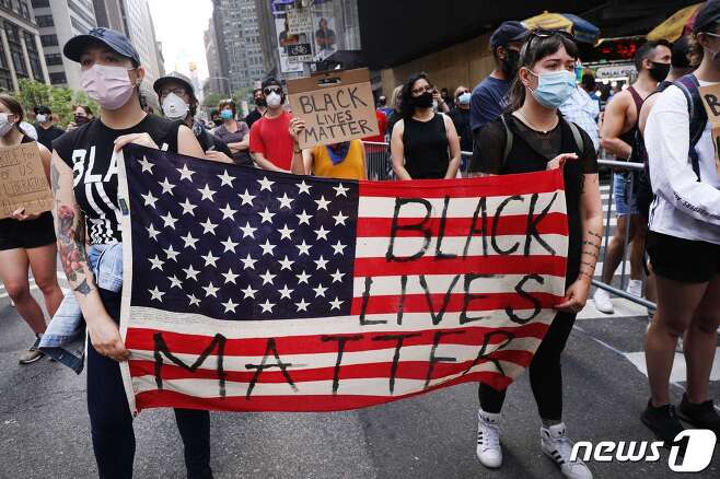 뉴욕에서 흑인 조지 플로이드의 죽음에 항의하는 시위대가 ‘흑인 생명도 소중하다’ 문구를 쓴 성조기를 들고 행진을 하고 있다. © AFP=뉴스1 © News1 우동명 기자