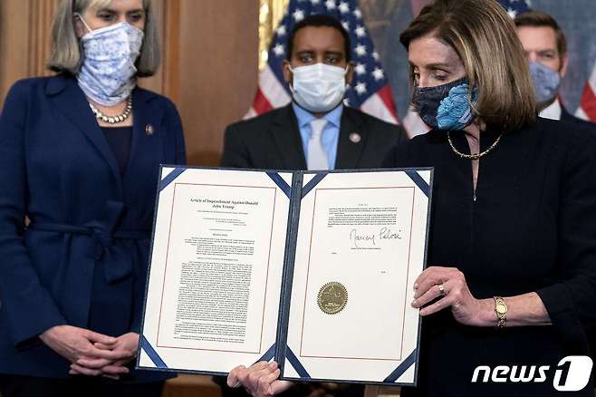 낸시 펠로시 하원의장이 13일(현지시간) 워싱턴 DC 의사당에서 도널드 트럼프 대통령에 대한 탄핵소추안에 서명한 문서를 들어 보이고 있다. © AFP=뉴스1