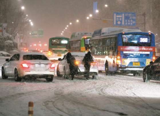 서울 전역에 대설주의보가 발효된 6일 오후 서울 삼성역 인근 도로에서 시민들이 차를 밀고 있다. 연합뉴스