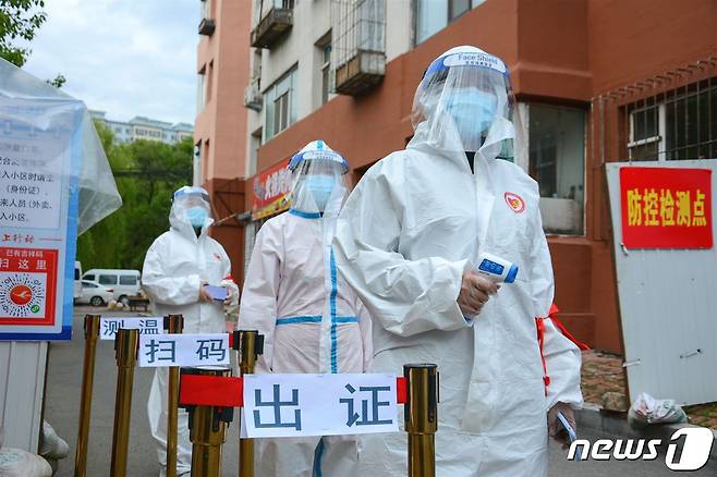 지난해 5월25일 중국 지린성의 주거지에 설치된 검문소에서 보호복을 입은 자원봉사자들이 서 있다. © AFP=뉴스1