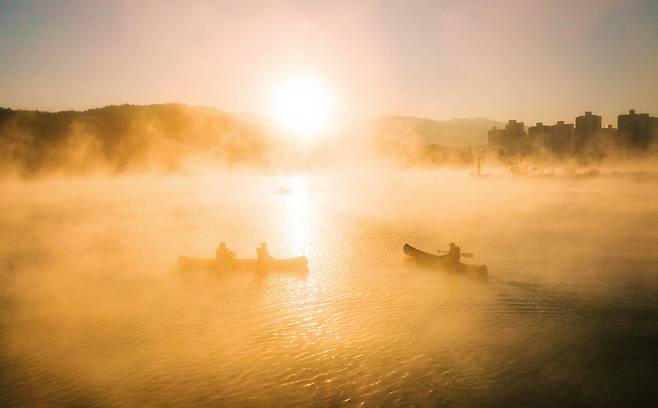 People travel in canoes on the Soyang River in Gangwon Province on Jan. 6. (Yonhap)