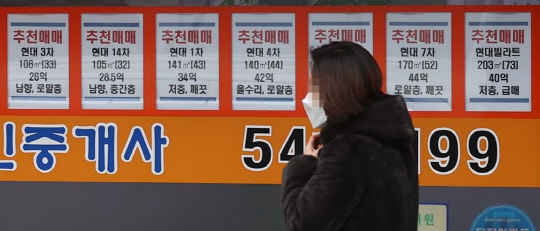 한 시민이 서울 압구정동의 부동산 매물 시세 정보가 적힌 공인중개업소 게시판 앞을 지나가고 있다. <연합뉴스>