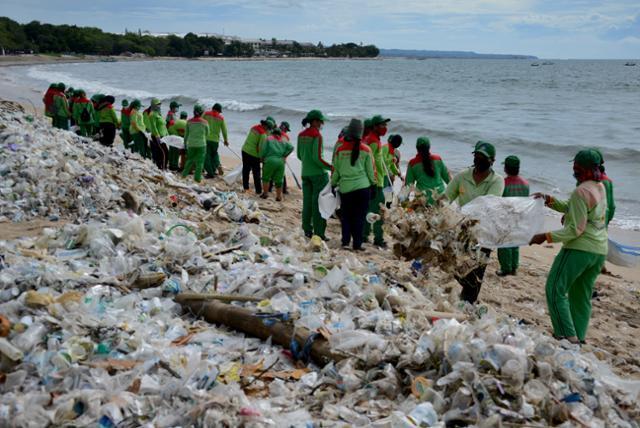 인도네시아 발리섬 남부 덴파사르의 꾸따해변에서 6일 관계자들이 해변에 쌓인 플라스틱 쓰레기를 치우고 있다. 덴파사르=AFP 연합뉴스