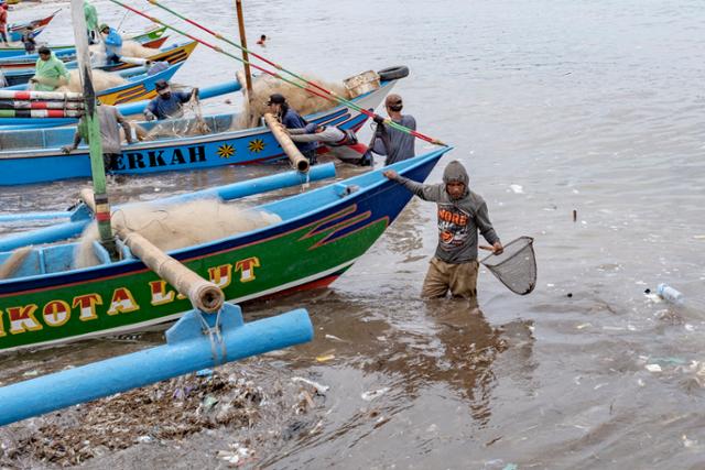 인도네시아 발리섬 끄동아난의 어촌에서 18일 어부들이 플라스틱 쓰레기가 덮인 해변에서 작업을 하고 있다. 발리=EPA 연합뉴스