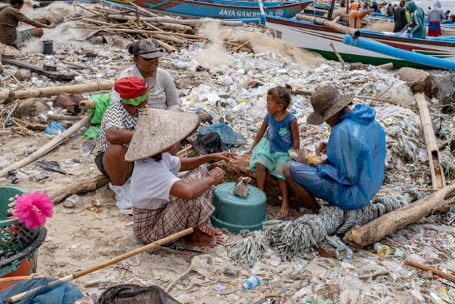 인도네시아 발리섬 끄동아난의 어촌에서 18일 어부들이 플라스틱 쓰레기가 덮인 해변에 앉아 있다. 발리=EPA 연합뉴스