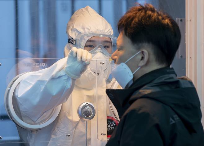 A medical worker collects nasal sample to check for COVID-19 at a diagnostics center made near the Seoul Station. (Yonhap)