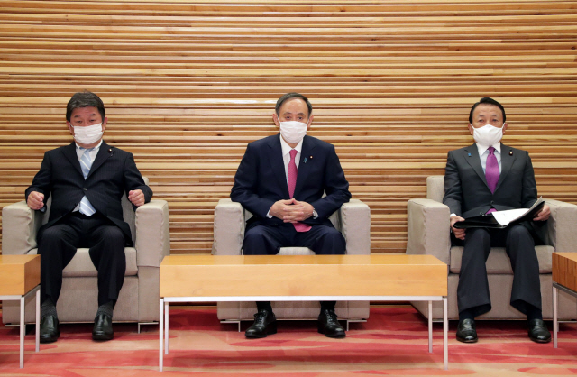 22일 도쿄 총리 관저에서 열린 각의에 참가한 스가 요시히데(가운데) 일본 총리가 모테기 도시미쓰(왼쪽) 외무상, 아소 다로 부총리 겸 재무상과 나란히 앉아 있다./AFP연합뉴스
