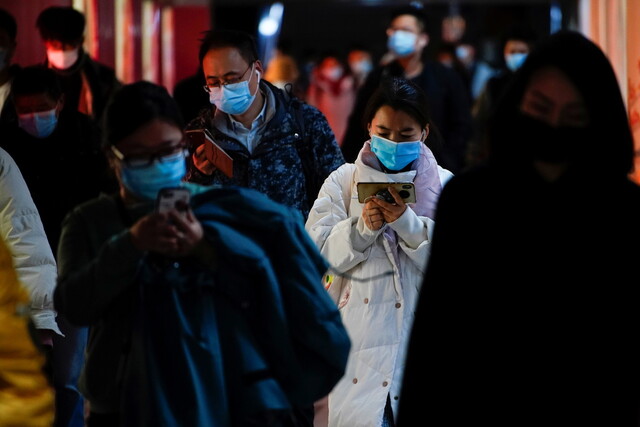 25일 중국 경제중심지인 상하이의 지하철역에서 마스크를 쓴 시민들이 휴대전화를 들여다보며 걷고 있다. 상하이/로이터 연합뉴스