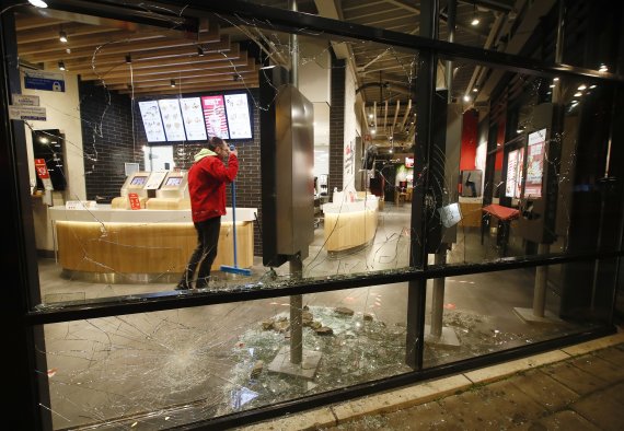 25일(현지시간) 네덜란드 로테르담의 한 패스트푸드 매장에서 한 직원이 깨진 유리창을 쓸고 있다.AP뉴시스