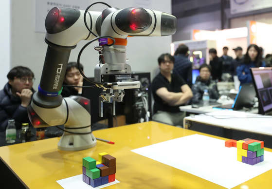 Visitors look at a robotic arm at an industrial technology exhibition in Coex in southern Seoul in 2019. [YONHAP]