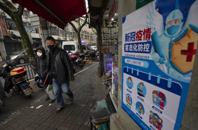 지난 26일 중국 상하이에서 코로나19 방역을 철저히 하자는 포스터 옆으로 시민들이 지나가고 있다. /EPA연합뉴스