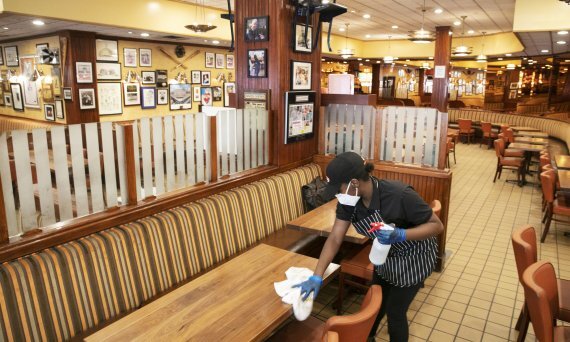 지난해 6월 29일 미국 뉴욕의 한 식당에서 점원이 텅 빈 매장을 소독하고 있다.AP뉴시스