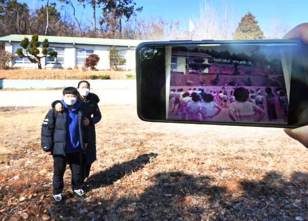 송 분교장과 경현군이 기념촬영을 하고 있다. 오른쪽 스마트폰에 표시된 1977년 당시 분교의 사진과 대비된다.