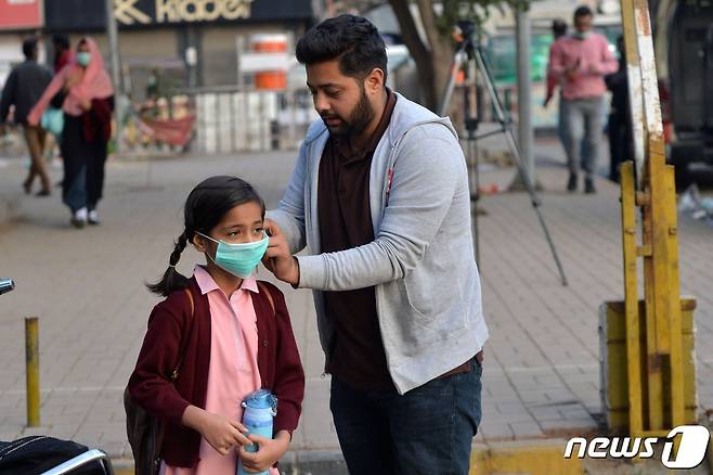 파키스탄에서 코로나19 백신 접종이 시작한 2021년 2월 1일(현지시간) 카라치 거리에서 한 남성이 아이에게 마스크를 씌워주고 있다.  © AFP=뉴스1
