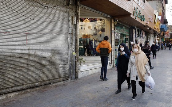 지난해 3월 12일 이란 테헤란의 한 전통시장 근처를 지나고 있는 사람들. 이날 이란은 IMF에 긴급 자금을 요청했다. [AFP=연합뉴스]