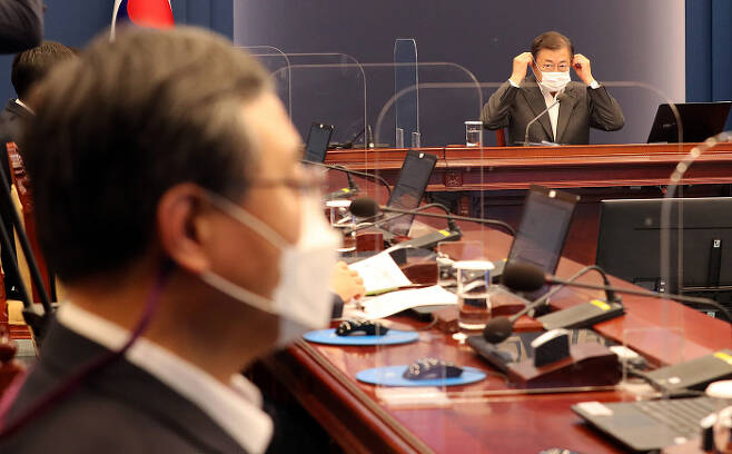 문재인 대통령이 22일 청와대 여민관에서 열린 수석·보좌관 회의에서 발언을 한 뒤 마스크를 쓰고 있다. 왼쪽은 신현수 청와대 민정수석.  청와대사진기자단