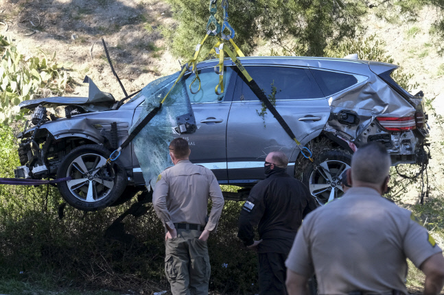 타이거 우즈가 24일(한국시간) 혼자 타고 있던 차량이 전복 사고가 나 골프팬들이 충격에 빠졌다. LA지역 보안관들이 우즈의 차량이 견인되는 모습을 지켜보고 있다. LA(미 캘리포니아주) | AP연합뉴스