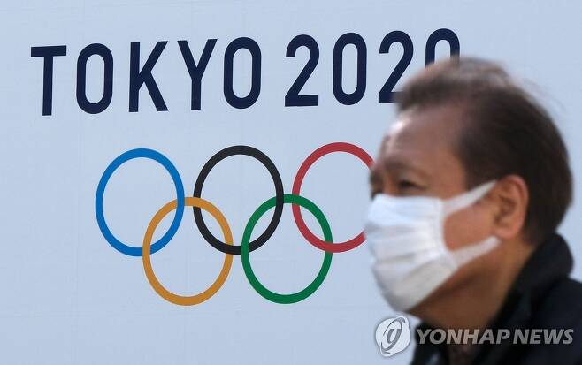 올림픽 엠블럼 앞을 지나가는 도쿄 시민 [도쿄 AFP=연합뉴스 자료사진]