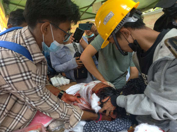 미얀마에 군부 쿠데타가 발생한 지 4주가 되는 28일 양곤에서 제2차 총파업에 동조한 이들이 군경이 총격을 가해 다친 남성을 구호하기 위해 안간힘을 쓰고 있다.양곤 EPA 연합뉴스