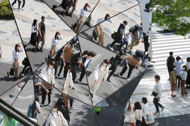 마스크를 쓴 시민들이 지난달 31일 일본 도쿄의 한 빌딩 벽에 있는 거울에 비치고 있다. 도쿄=AP 뉴시스