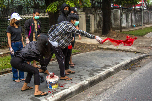 지난 6일(현지시간) 미얀마 양곤에서 반 쿠데타 시위대가 거리에 붉은 페인트를 뿌리고 있다. 양곤=AP·뉴시스