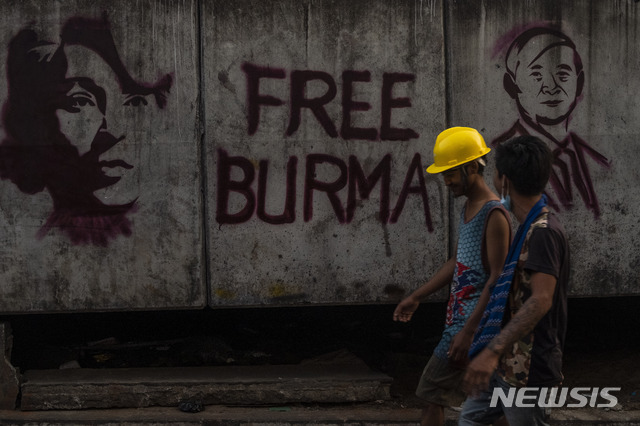 [양곤=AP/뉴시스]18일 미얀마 양곤에서 반 쿠데타 시위대가 윈민 미얀마 대통령과 아웅산 수지 국가고문의 그림이 그려진 벽화 앞을 지나고 있다. 2021.03.18.