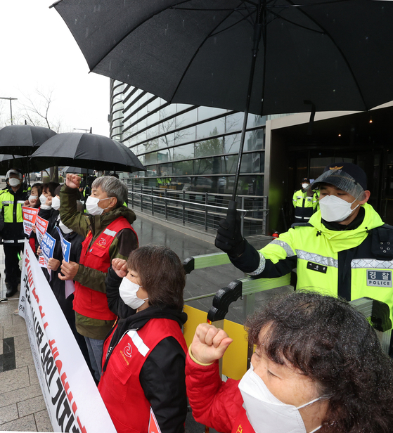16일 주한일본대사관 앞에서 한 경찰이 '일본 후쿠시마 원전 방사능 오염수 해양방출 결정 규탄 기자회견을 하는 '함께살자 노량진수산시장 시민대책위' 회원에게 우산을 씌워주고 있다. [연합뉴스]