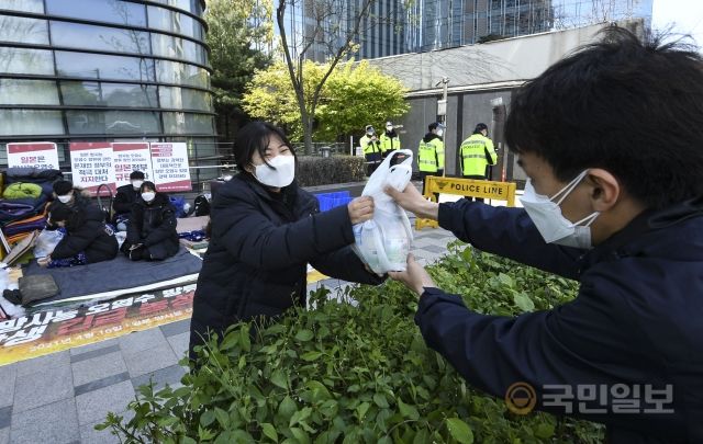 18일 서울 종로구 일본대사관 입주 건물 앞에서 일본 방사능 오염수 방류 저지 대학생 긴급농성단이 농성을 벌이고 있는 가운데 한 시민이 간식을 전달하고 있다.
