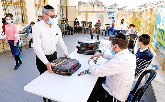 올 2월 이스라엘 브네이브라크 접종소에서 코로나19 백신을 맞은 사람이 무료로 나눠주는 피자를 챙겨가고 있다. AFP