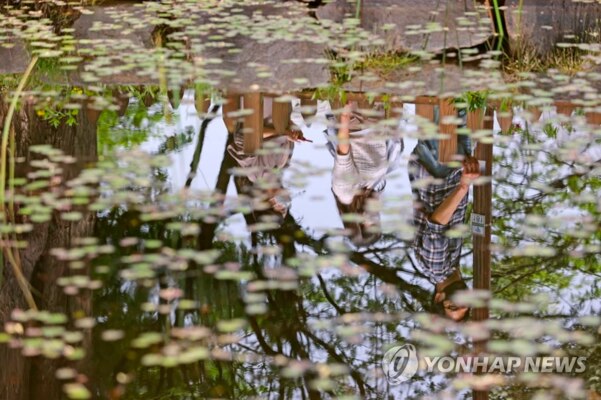 22일 정오를 넘긴 시간 서울 여의도공원 연못에 가벼운 차림의 시민들 모습이 반영되고 있다.