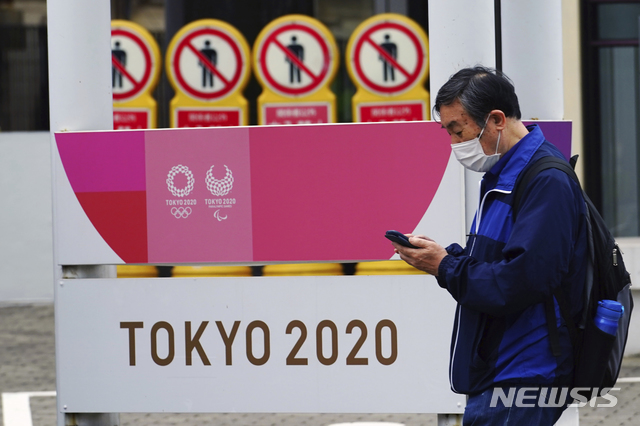 [도쿄=AP/뉴시스]이달 11일 일본 도쿄에서 코로나19 확산 방지를 위해 마스크를 쓴 한 남성이 2020 도쿄올림픽·장애인올림픽 홍보물 앞을 지나가고 있다. 2021.05.21.