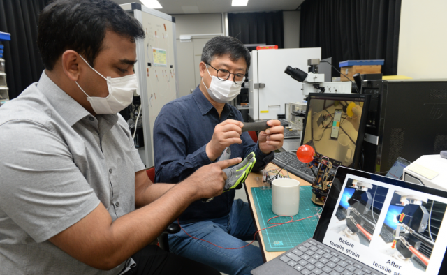 ETRI의 최춘기(오른쪽) 책임연구원이 슈브라몬달 UST 학생연구원과 함께 복합 소재를 기반으로 만든 내방사선 압력-온도 복합 센서를 장갑에 적용해 시연하고 있다.