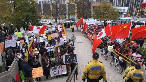2014년 10월 29일 캐나다 토론토교육청 앞. 이날 교육청 위원회는 공자학원 제휴 중단 안건에 대해 찬성 20표, 반대 2표의 결정으로 공자학원을 토론토 교육 기관에서 퇴출하기로 결정했다. 이에 앞서 공자학원 반대 시위대(왼쪽)과 중국 정부 지지 시위대(오른쪽)가 교육청 앞에서 세를 겨뤘다. 다큐 ‘공자라는 미명 하에’ 캡처