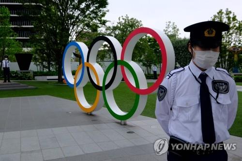 지난달 18일 도쿄올림픽 개최 반대 시위가 벌어진 도쿄의 일본올림픽조직위원회 본부 앞 올림픽 조형물 앞에서 경비원이 경계를 서고 있는 모습. (AFP=연합뉴스 자료사진)