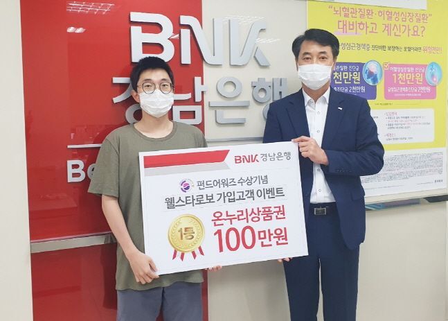 김남훈(오른쪽) BNK경남은행 영업점장이 BNK웰스타로보 가입고객 이벤트 1등 당첨자에게 전통시장온누리상품권 100만원권 증서를 전달하고 있다.ⓒBNK경남은행