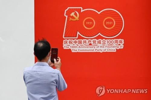 지난 2일 베이징에서 한 남성이 중국 공산당 100주년 홍보물을 촬영하고 있다. [AFP=연합뉴스]