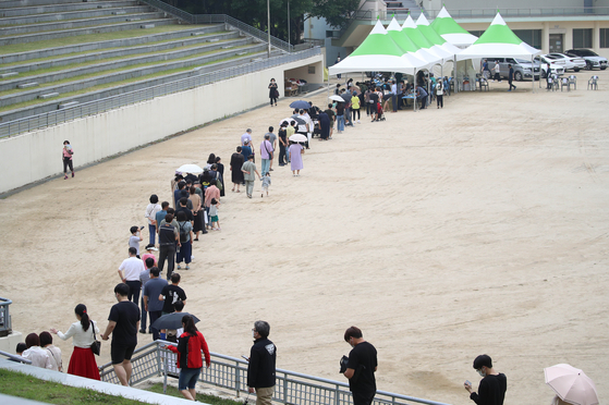 People stand in line to take coronavirus tests at a screening clinic in the southeastern city of Daegu on Monday. Korea's daily new virus cases spiked to an over two-month high as a series of cluster infections were reported in the wider Seoul area amid jitters over growing Covid-19 variant cases. [YONHAP]