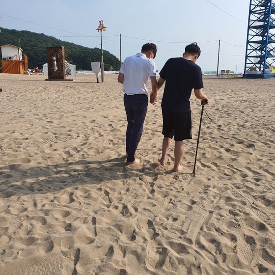 김호영(오른쪽)씨가 바닷가 모래밭에서 아버지의 부축을 받으면서 걷고 있다 .사진 김두경씨 제공