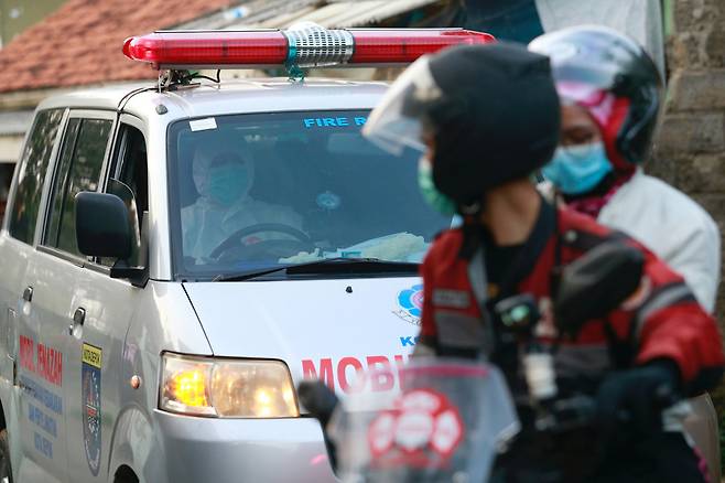 인도네시아에서 코로나19 응급환자를 이송하는 구급차가 교통체증이 심한 구간을 빠르게 이동할 수 있도록 길을 터주는 자원봉사를 하는 ‘오토바이 부대’의 모습. 사진 로이터 연합뉴스