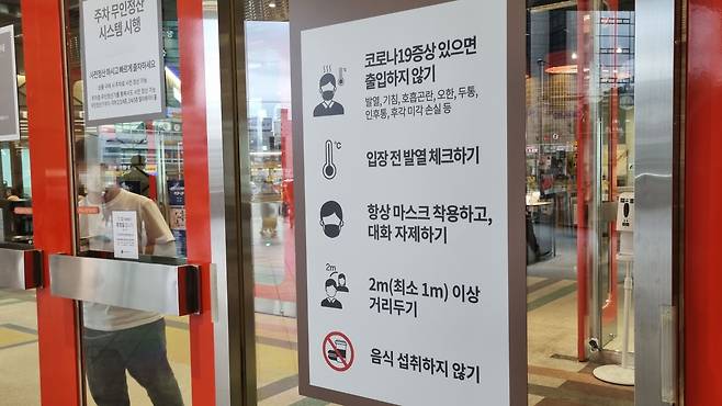 지난 8일 오후 7시쯤 서울 영등포구 롯데백화점 영등포점 출입문에 방역수칙 안내문이 붙어있다. 내부 출입문에는 체온측정기와 손소독제만 비치돼있었다. /이은영 기자