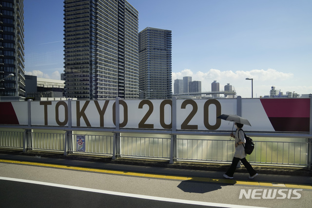 [도쿄=AP/뉴시스] 17일 한 여성이 '도쿄 올림픽 2020' 현수막이 붙어 있는 도쿄의 한 교량을 지나고 있다. 2021.07.17.