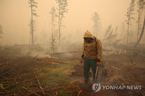 지난 17일 사하공화국의 한 화재 현장에서 당국자가 진화작업을 펼치는 모습. [로이터=연합뉴스]