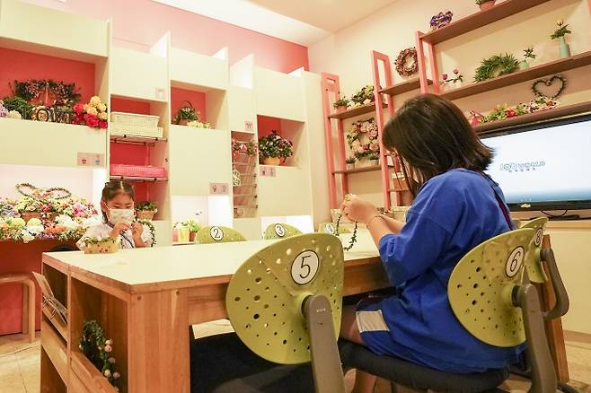 꽃집 체험실. 어린이가 화관을 만들고 있다.