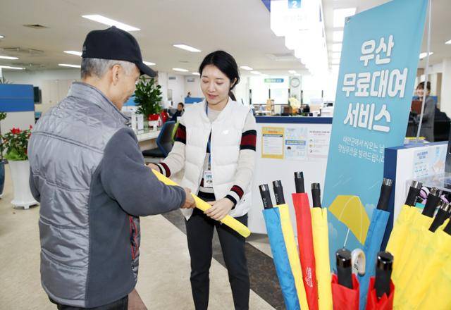 충남 태안군 관계자가 주민에게 우산을 무상으로 대여해 주고 있다. 태안군은 지난 6월부터 군내 다중이용시설 72곳에 무료 대여소를 설치하고 우산 약 1,500개를 비치해 두고 있다. 태안군청 제공