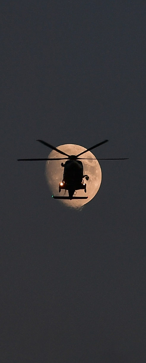 지난 19일 인천 영종도 하늘에서 밝게 뜬 달 앞으로 해경 구조헬기가 순찰 비행을 하고 있다.