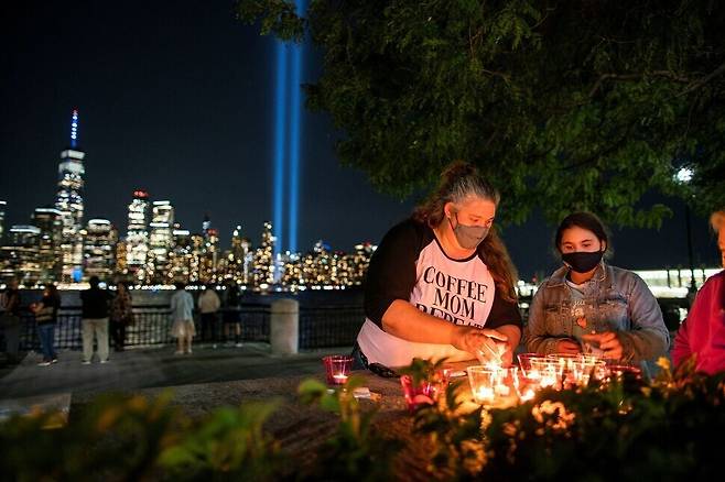 Americans gather in Exchange Place in Jersey City, New Jersey, and light candles on Saturday, the 20th anniversary of the Sept. 11 attacks. Across the Hudson River, One World Trade Center, reconstructed at the site of the attacks on the World Trade Center, beam blue lights skyward where the twin towers once stood. (Reuters/Yonhap News)