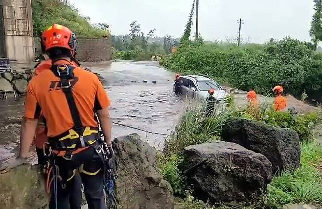 태풍 찬투의 간접 영향으로 제주에 많은 비가 내린 14일 오전 소방대원들이 물에 잠긴 제주시 용강동의 한 도로에서 고립된 차 안의 운전자를 구조하고 있다. 연합뉴스