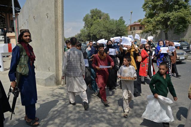 3일 아프가니스탄 카불에서 여성 인권 존중을 요구하는 여성 시위대 바로 옆에 총을 든 탈레반 대원이 서 있다. 카불=AFP 연합뉴스