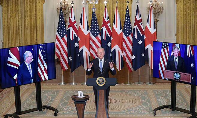 조 바이든 미국 대통령(가운데)이 15일(현지시간) 백악관 이스트룸에서 화상으로 참여한 스콧 모리슨 호주 총리(왼쪽), 보리스 존슨 영국 총리와 함께 3자 안보동맹 ‘오커스’(AUKUS) 발족을 발표하고 있다. 워싱턴=EPA연합뉴스